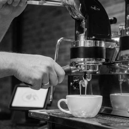 A barista pulling a double shot on a La Marzocca lever espresso machine